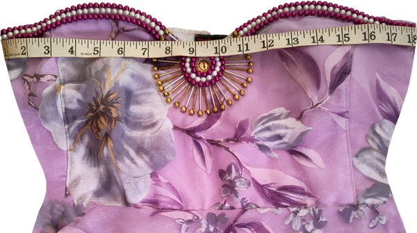 Woman wearing a strapless artistic handmade floral design beaded gown with purple accents on a white background