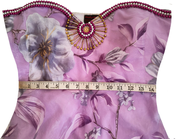 Woman wearing a strapless artistic handmade floral design beaded gown with purple accents on a white background