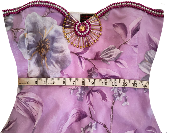 Woman wearing a strapless artistic handmade floral design beaded gown with purple accents on a white background