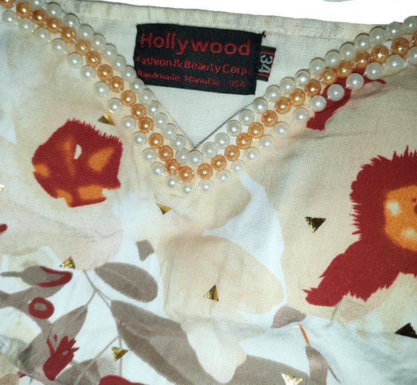 Close-up of a decorative fabric with floral patterns and pearl embellishments, featuring the 'Hollywood Fashion & Beauty Corp.' label.